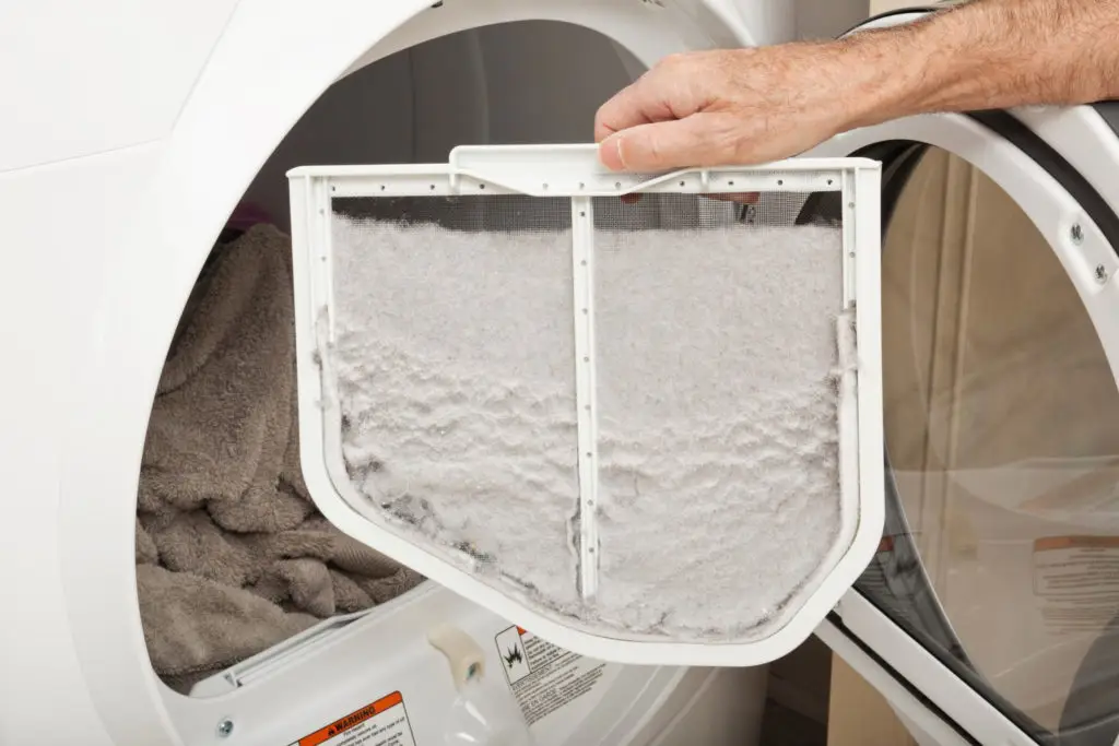 A dryer lint trap filled with white lint.