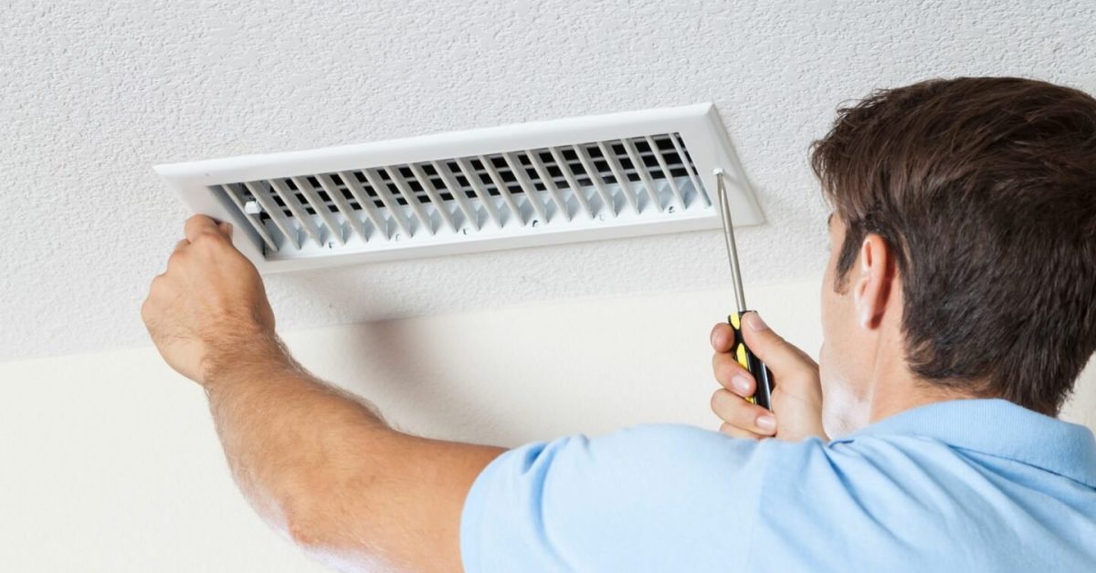 A worker unscrews an air vent to perform air duct repair