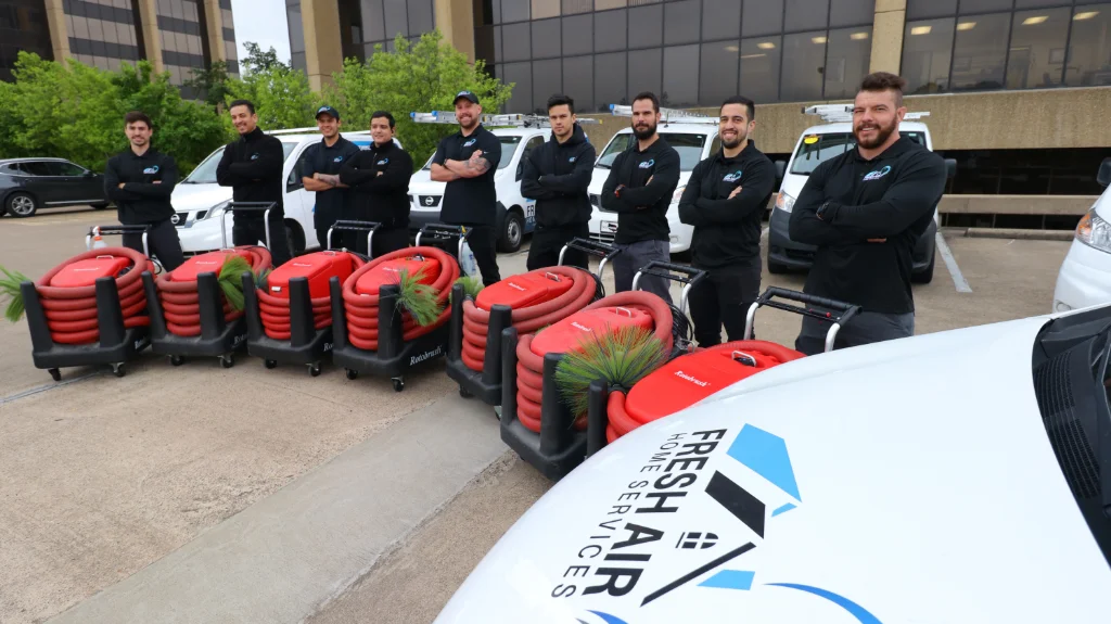 Fresh Air Home Services team standing beside service vans and red air duct cleaning equipment.