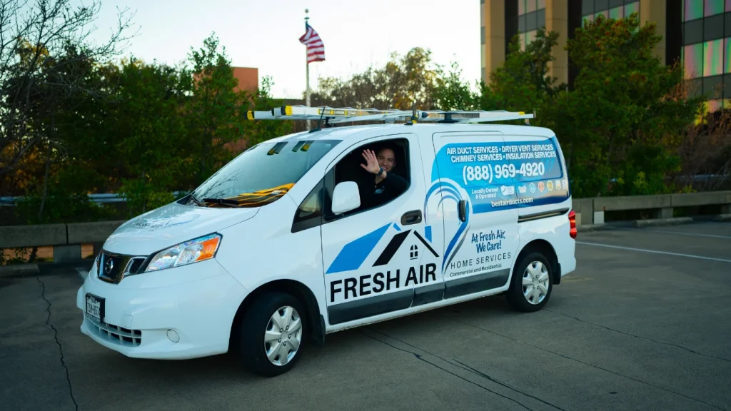 Technician waving from Fresh Air Home Services van with company logo and contact number in parking lot.